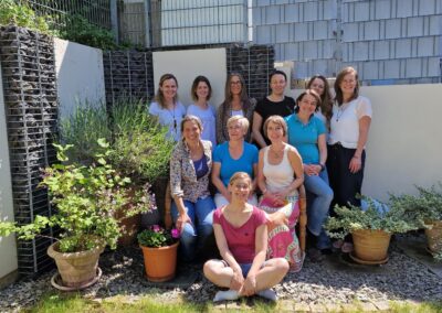 NLP-Premium-Teilnehmerinnen sitzen mit Isabel Ihm im Freien und lachen in die Kamera